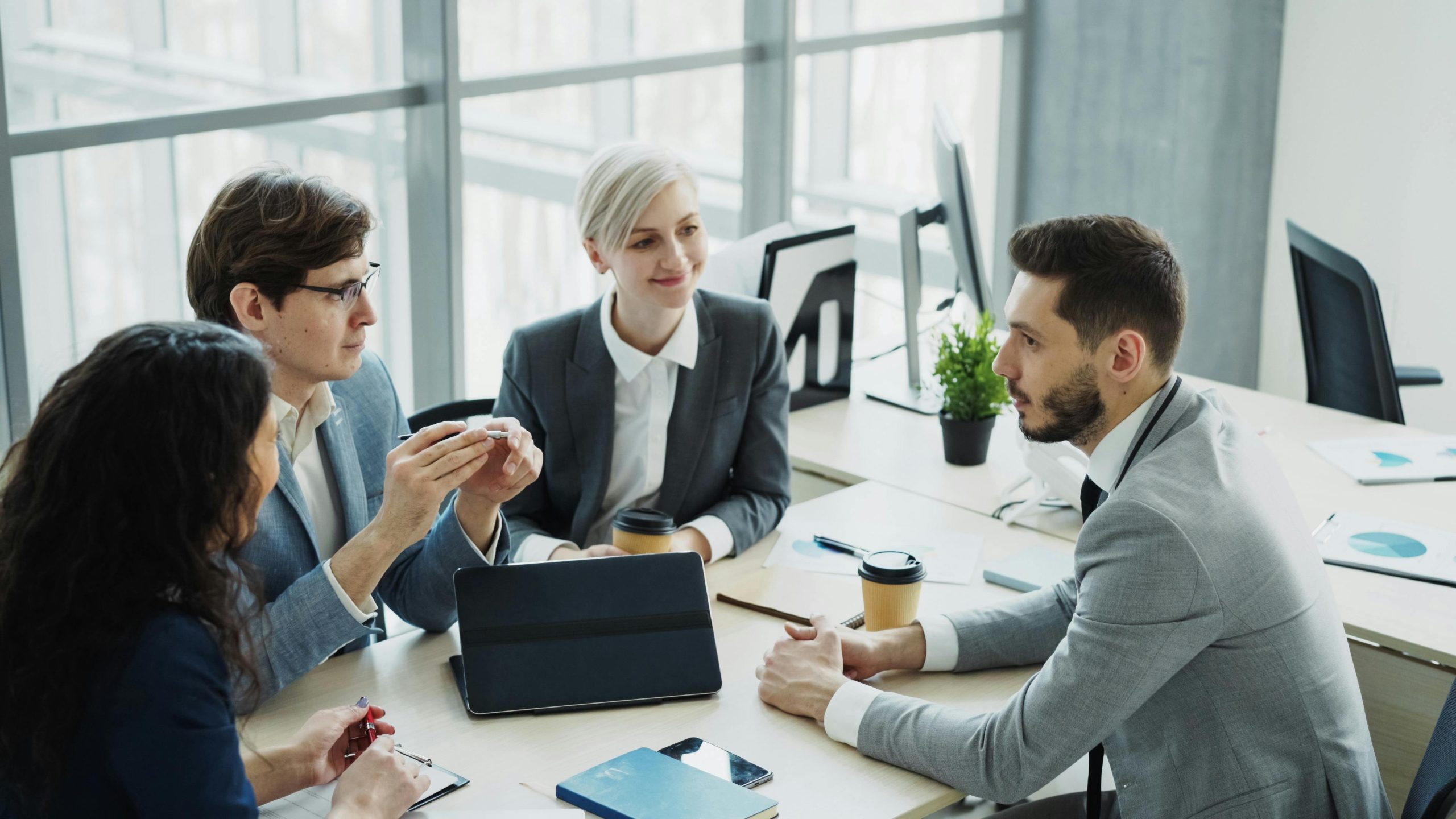 Group of professionals having a discussion in a modern office setting with natural light.